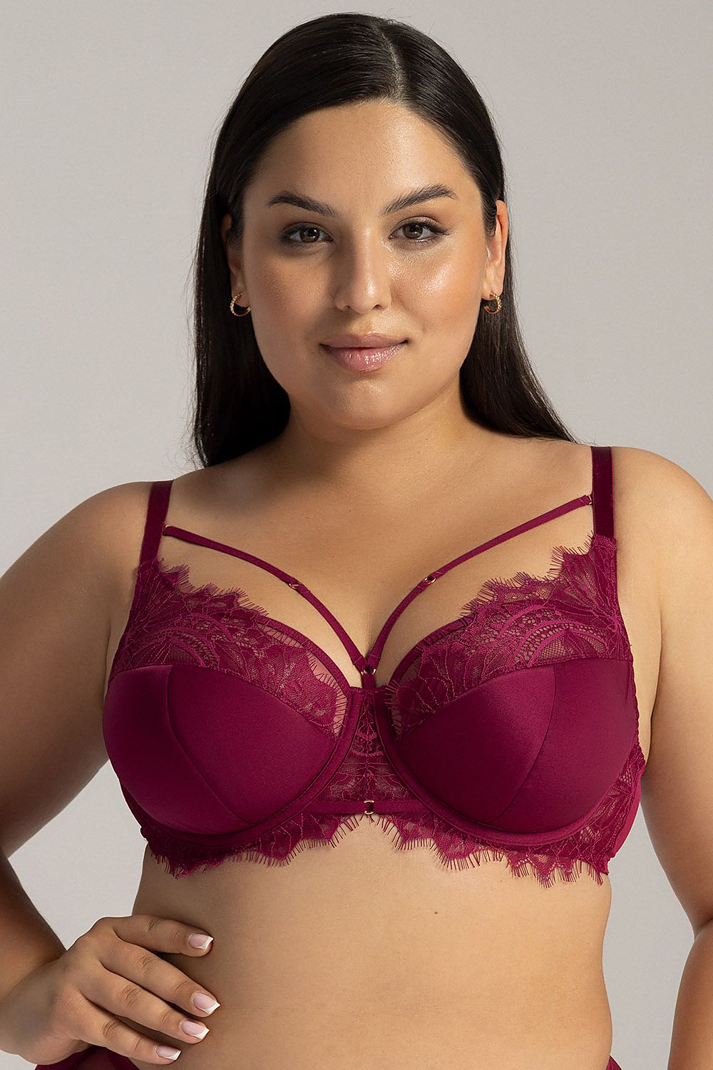 Woman wearing a burgundy lace bra against a plain background